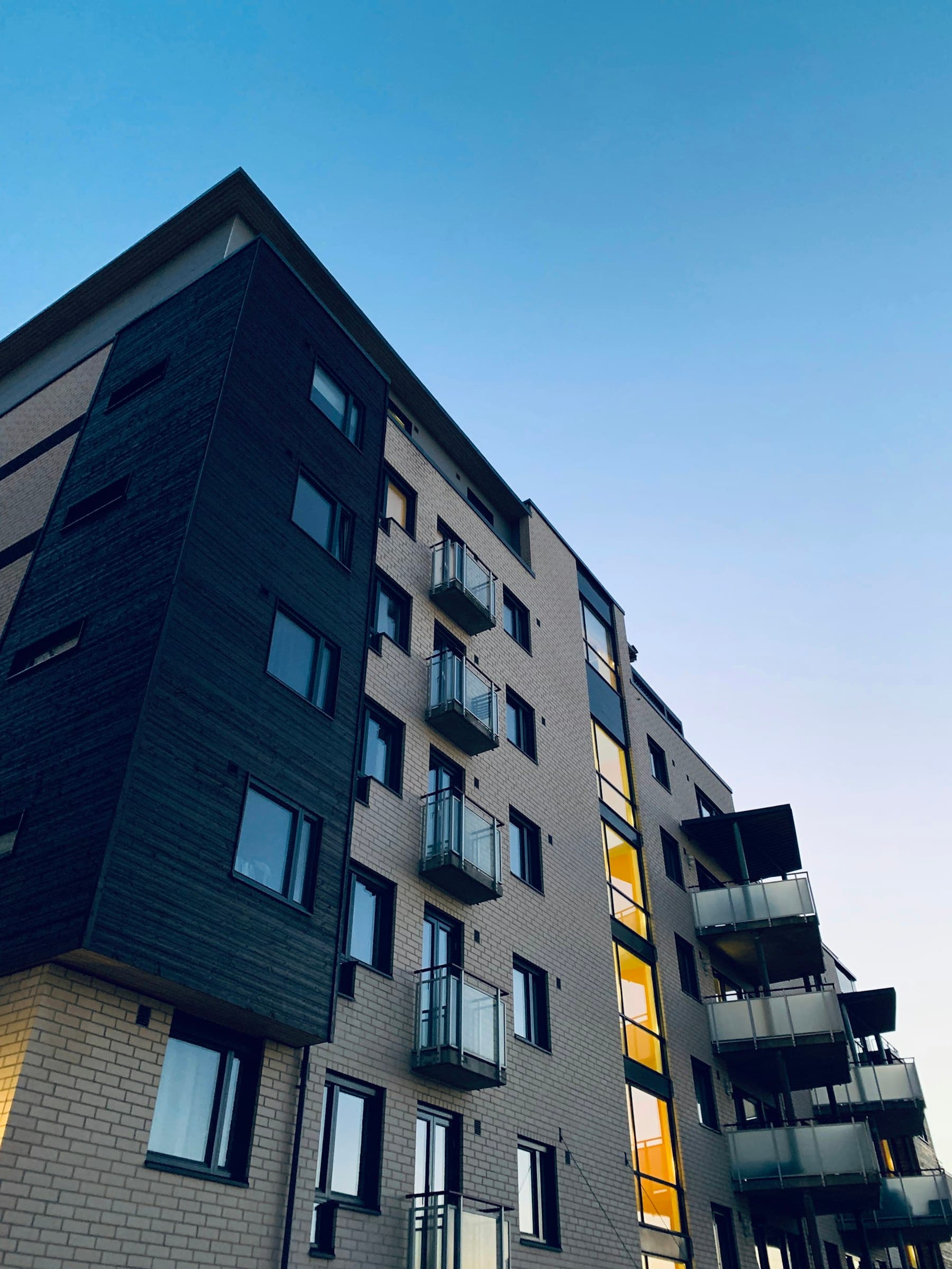 Immeuble contemporain gris et jaune au crépuscule — balcons filants
