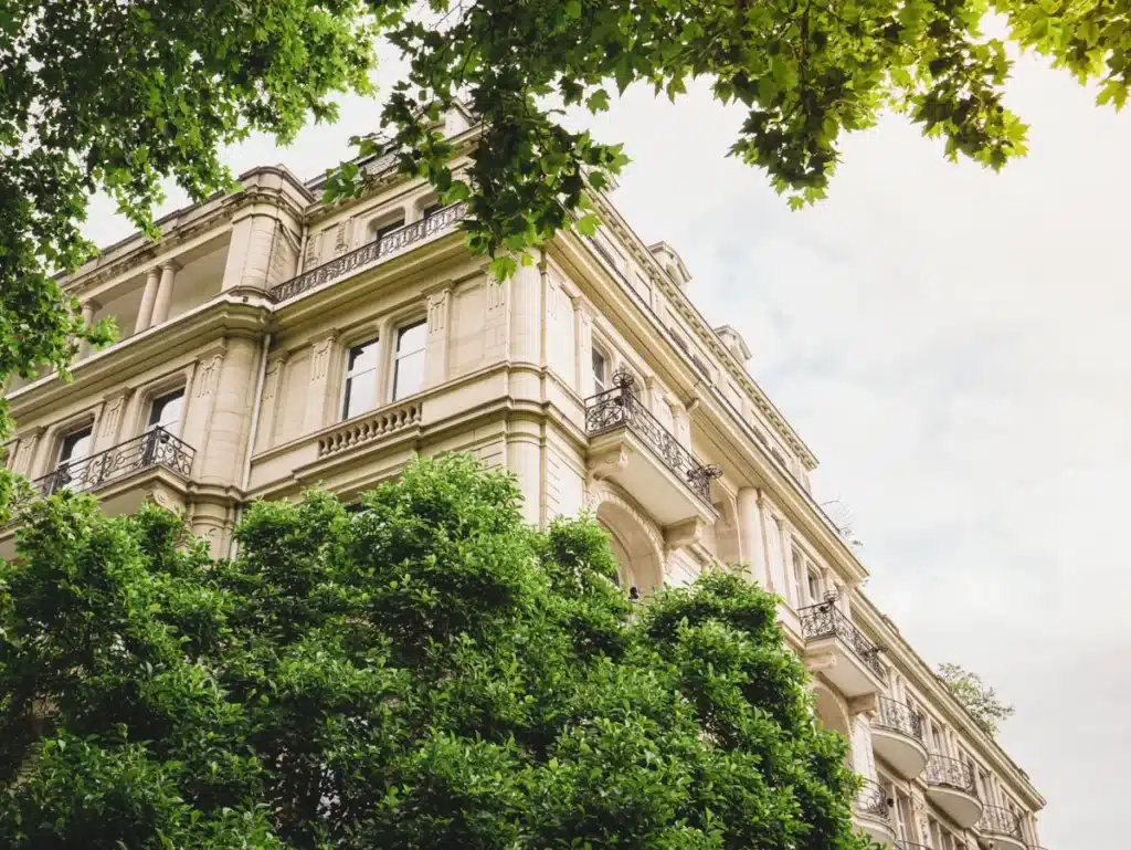 Vue d'un immeuble résidentiel classique entouré de verdure, représentant une solution immobilière harmonieuse entre nature et architecture.